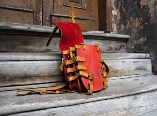 Oryginalny oldschoolowy skórzany plecak w kolorze czerwonym z wygodną kieszonką na plecach i długim paskiem